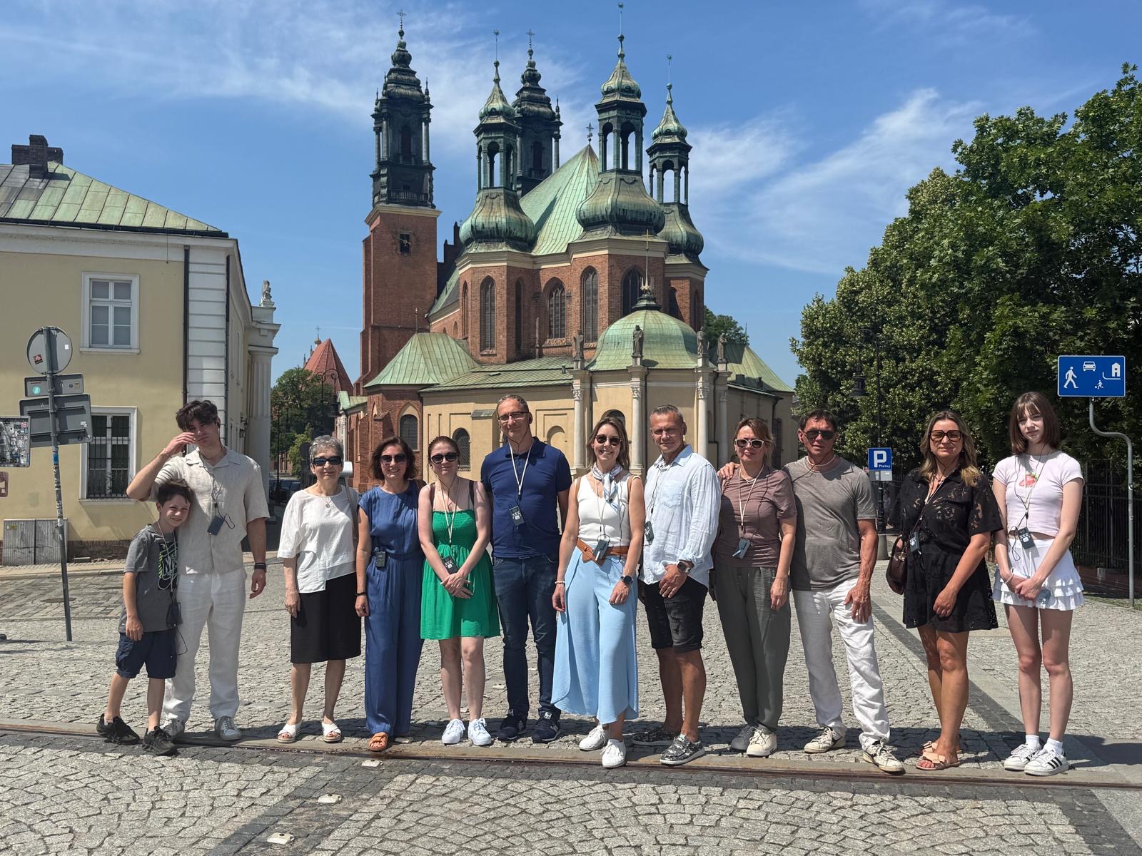 Grupa zwiedzających pozuje przed poznańską katedrą